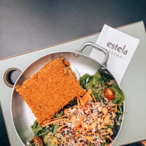 Quibe vegetariano de trigo branco recheado com abóbora e acompanhado de mix de folhas verdes, tomatinho cereja, cenoura julienne e granola salgada